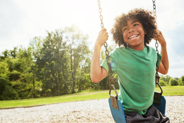 The simple joys of childhood Cropped shot of a young boy playing on a swing at the park innocence stock pictures, royalty-free photos & images