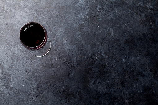 Red wine glass on stone background. Top view with copy space