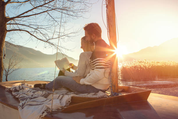 istock Young couple relaxing by the lake reading a book 640213304