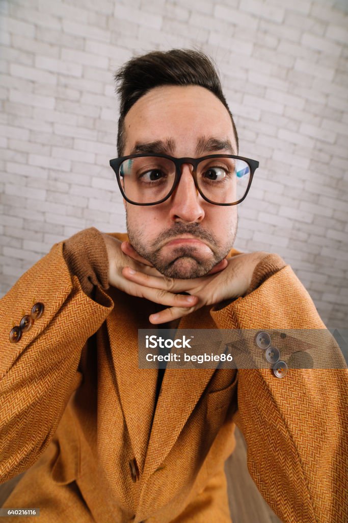 Funny nerd with geek glasses making facial expression Funny nerd with geek glasses making facial expression. Shot in ultra wide perspective.Funny nerd with geek glasses making facial expression. Shot in ultra wide perspective. Adult Stock Photo