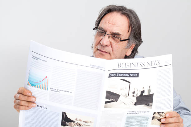 istock Senior man reading newspaper on gray background 640221572
