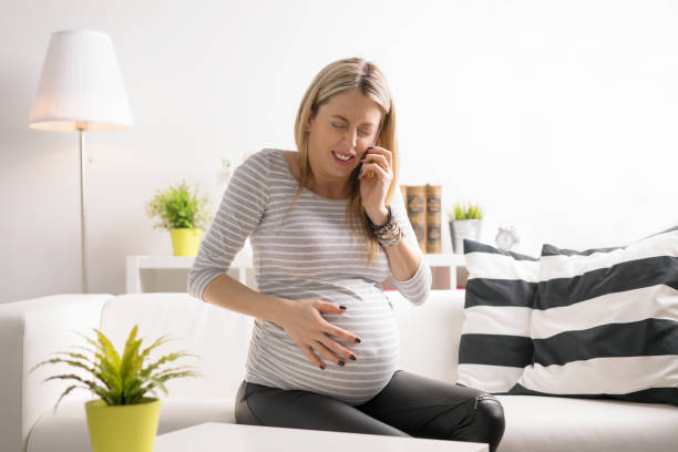 pregnant woman in labor calling hospital - urgency body care young adult people imagens e fotografias de stock