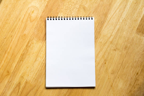 istock White note book place on wooden table background 640226400