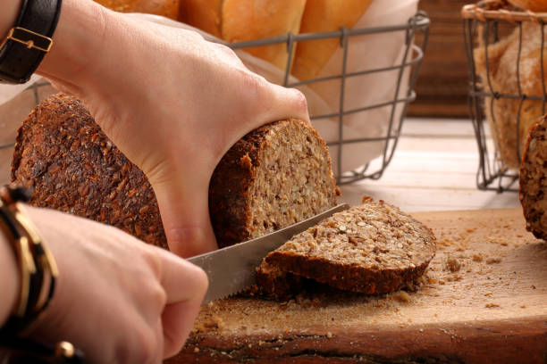 istock Woman cut whole grain bread on a wooden board 640226598