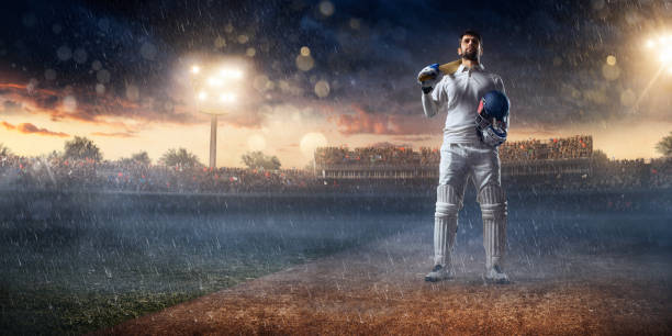 Cricket player batsman on the stadium Cricket player standing on a cricket field. The batsman is wearing unbranded sports cloth and equipment. The bleachers full of people are blurred behind the player. There is intentional lenseflares on the image. cricket player photos stock pictures, royalty-free photos & images