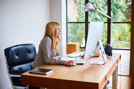 Shot of a young woman working on a computer while sitting at a desk in her home office