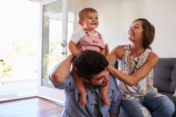 istock Parents Playing With Baby Daughter On Sofa At Home 640228544