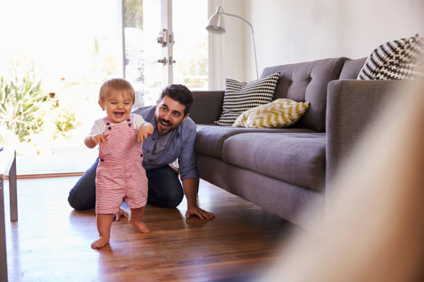 les parents regardent la petite fille faire les premiers pas à la maison - native habitat photos et images de collection