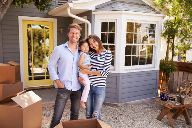 retrato de la familia emocionada de pie fuera de un nuevo hogar - women moving house men relocation fotografías e imágenes de stock