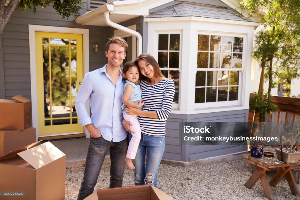Ritratto di famiglia eccitata in piedi fuori da una nuova casa - Foto stock royalty-free di Famiglia