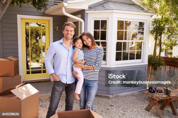 Portrait Of Excited Family Standing Outside New Home Stock Photo - Download Image Now