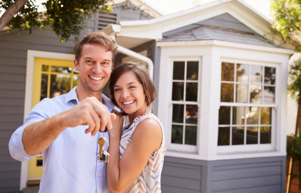 Couple With Keys Standing Outside New Home Couple With Keys Standing Outside New Home home ownership stock pictures, royalty-free photos & images
