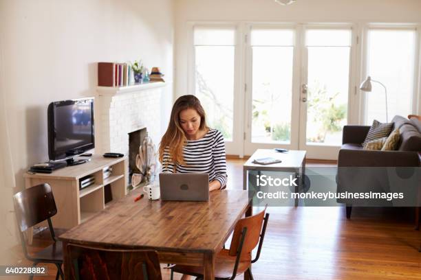 Woman Working From Home Using Laptop On Dining Table Stock Photo - Download Image Now