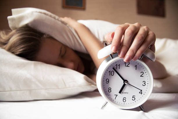 istock Woman hiding under pillow upon waking up with alarm clock 640230446