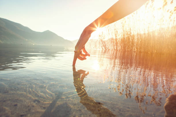 istock Finger touches surface of mountain lake 640230510