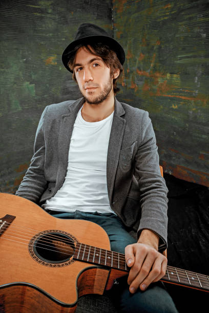 istock Cool guy sitting with guitar on gray background 640231912