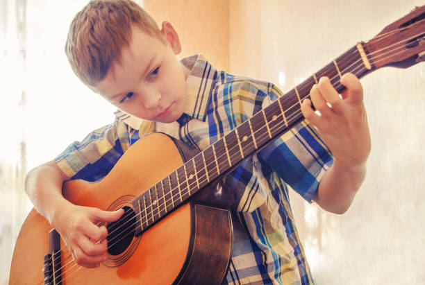 istock Boy learning to play the acoustic guitar. In a blue 640236586