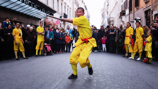 Rome, Italy - January 28, 2017: Celebration of the Chinese New Year in Rome, the year of the rooster. monk athlete in martial arts, he performs with the sword in the street during the procession.