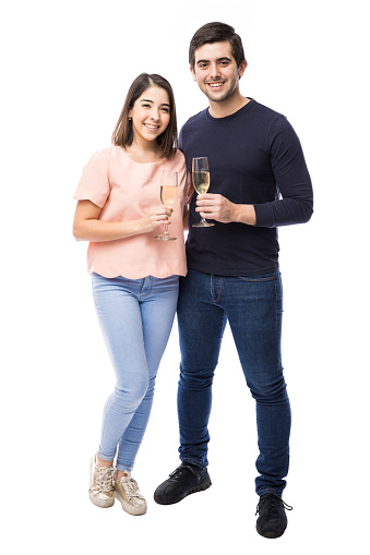 Full length portrait of a beautiful young couple holding glasses with champagne and making a toast