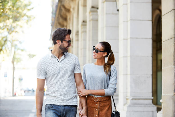 Enjoying a day in the city Shot of an affectionate young couple walking together in the city urbane stock pictures, royalty-free photos & images