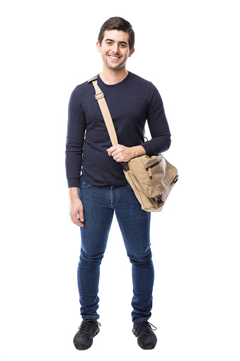 Full length view of a handsome Hispanic university student in a white background