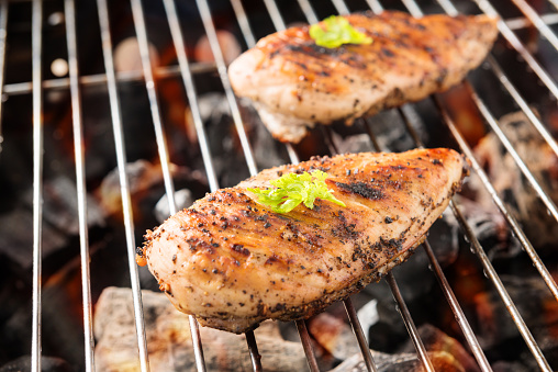 Grilled chicken breast on the flaming grill.
