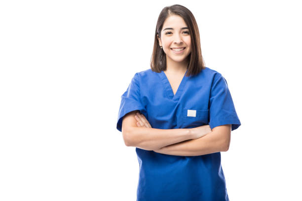 Pretty young nurse with arms crossed Portrait of a good looking young nurse with her arms crossed in a white background medical scrubs stock pictures, royalty-free photos & images