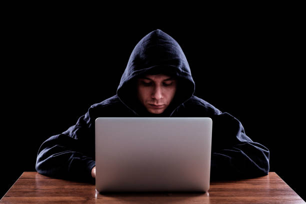 istock Hacker in dark hoody sitting in front of notebook 640241978