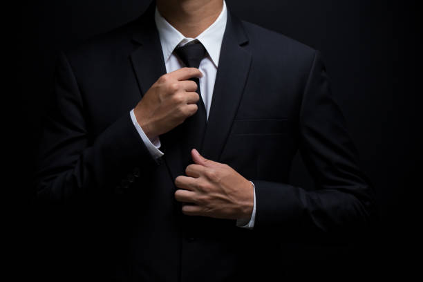 istock Man in black suit and adjusting his necktie 640244524