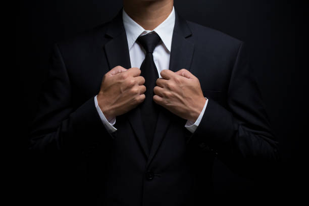 istock Man in black suit and adjusting his necktie 640245076