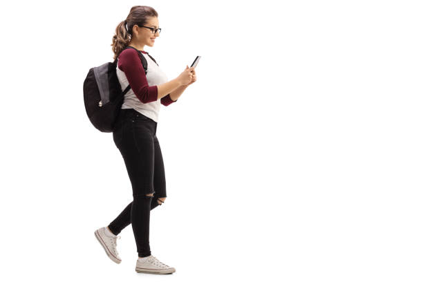 istock Female student walking and looking at mobile phone 640245110