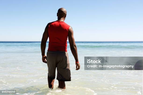 African Man Walking In To The Sea Water Stock Photo - Download Image Now - Wading, Men, Active Lifestyle