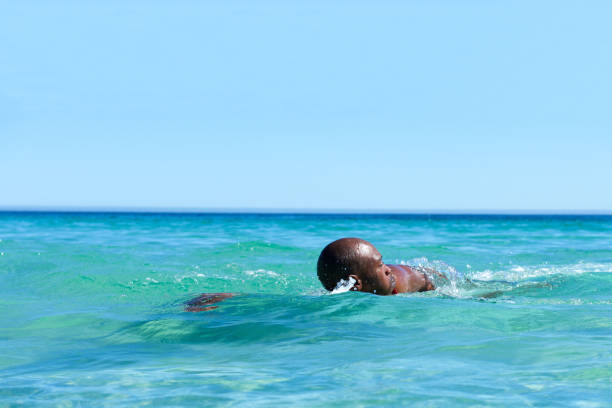 Portrait of fit young african man swimming in ocean water