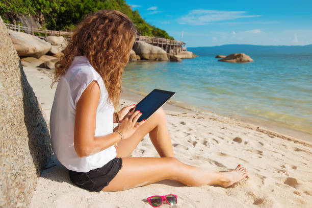 istock woman with tablet on the beach 640248650