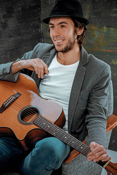 istock Cool guy sitting with guitar on gray background 640250006
