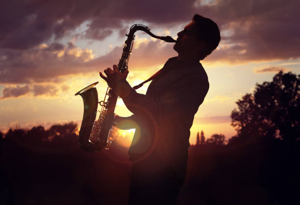 saxofonista tocando sax contra o pôr do sol - blues saxophone jazz musical instrument - fotografias e filmes do acervo