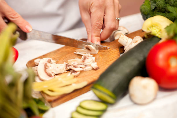 Woman in the kitchen cutting champignons on chopping board
