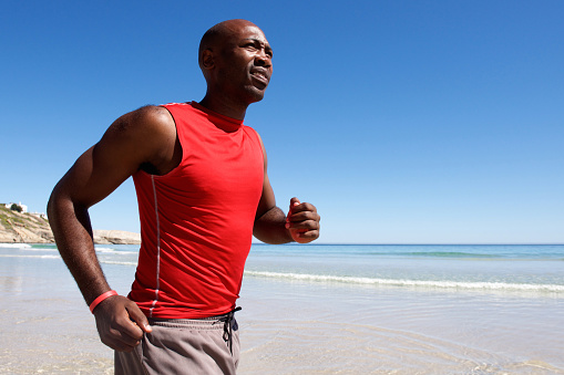 Portrait of healthy  african guy running along the seashore