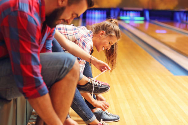Friends Putting On Bowling Shoes Stock Photo - Download Image Now - Ten Pin Friendship, Bowling Alley iStock