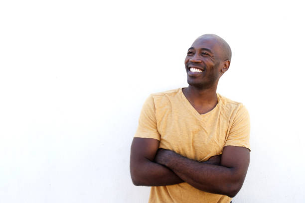 Portrait of laughing young afro american model standing with arms crossed against white background and looking away at copy space