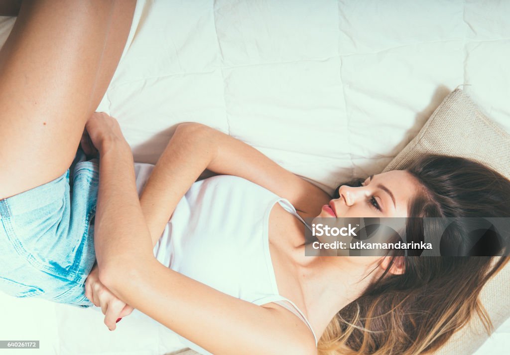 Woman stomach pain on bed top view Woman stomach pain on bed top view. Indor shot. Pain Stock Photo