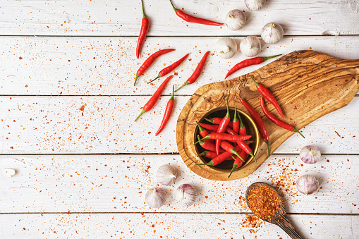 Red chili peppers with garlic scattered on a kitchen counter