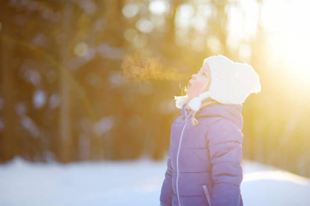 zabawna dziewczynka bawiąca się w zimowym parku - winter child coat baby girls zdjęcia i obrazy z banku zdjęć