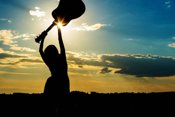 istock Silhouette woman playing guitar in sunset 640266000