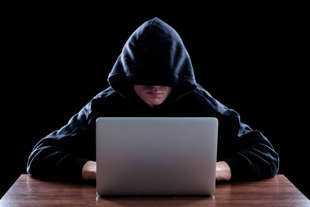 istock Hacker in dark hoody sitting in front of notebook 640267582