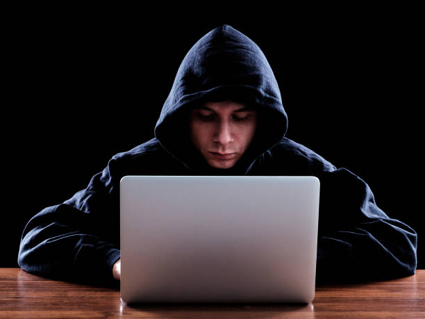 istock Hacker in dark hoody sitting in front of notebook 640268008