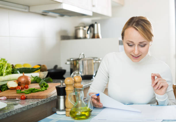istock Cheerful housewife signing papers in kitchen 640268108