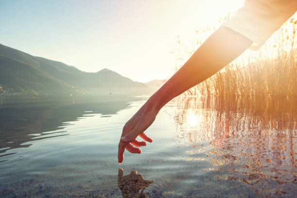 istock Finger touches surface of mountain lake 640271662
