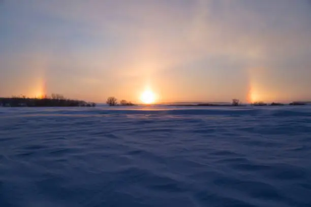 Snowy rural Minnesota landscape with sundogs at sunset.