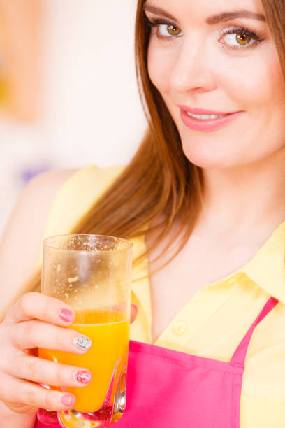 istock Woman in kitchen drinking fresh orange juice 640277632